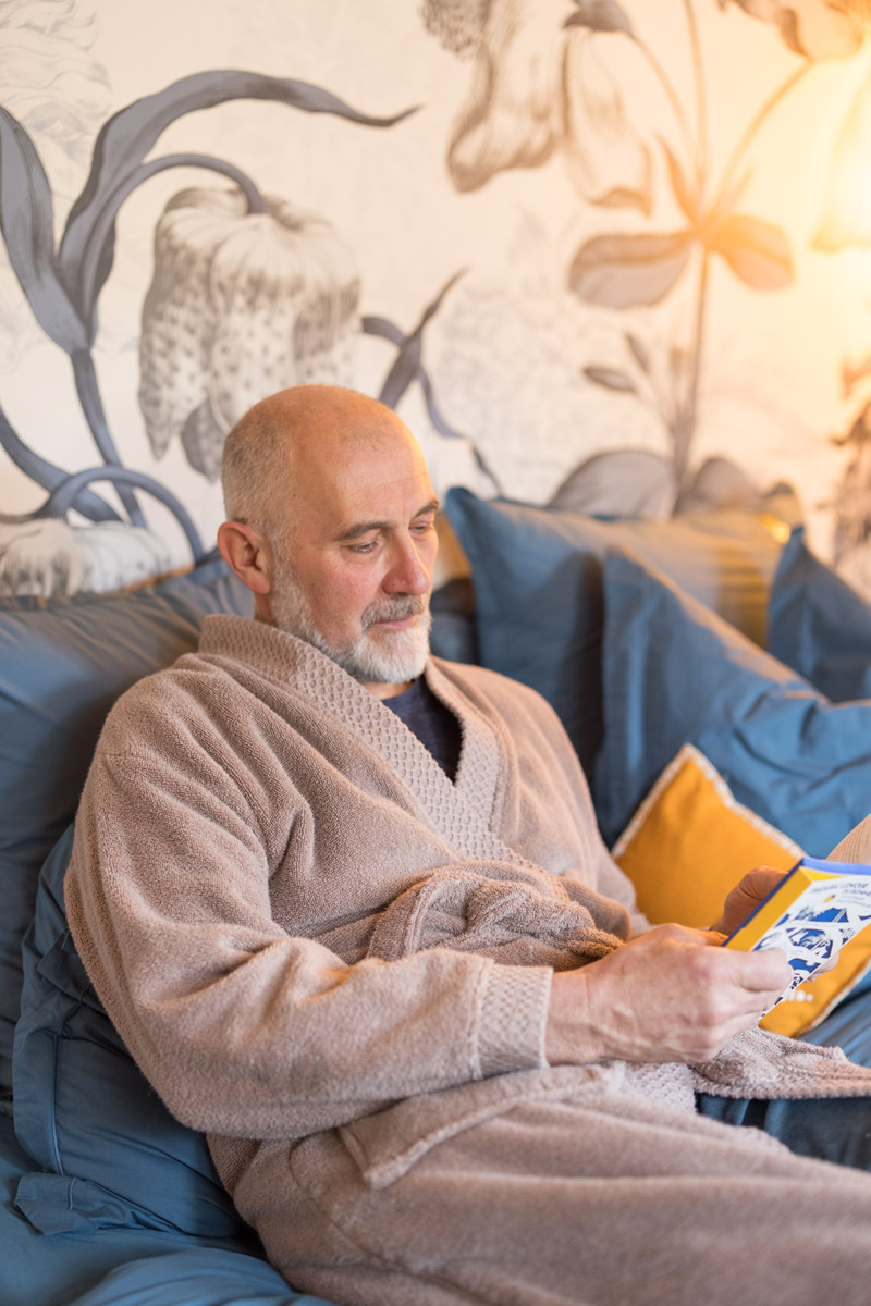 Photo d'une personne en train de lire sur le lit de la chambre Fleurs du gîte « À toi l'Aviateur ! » à Wattwiller - photo Marie Soehnlen
