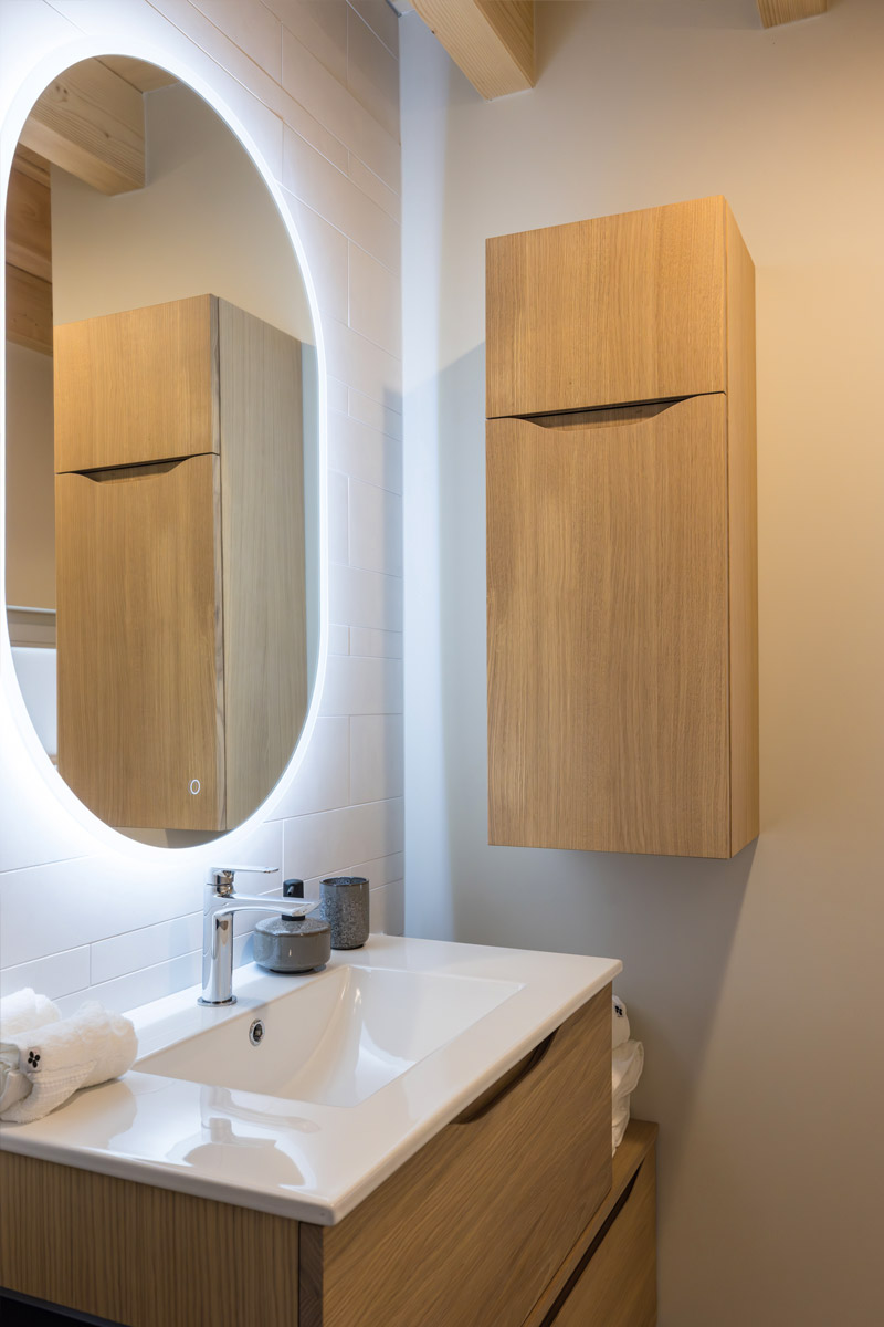 Photo du lavabo avec miroir éclairé et meuble de rangement de la salle de bain du gîte « À toi l'Aviateur ! » à Wattwiller - photo Marie Soehnlen
